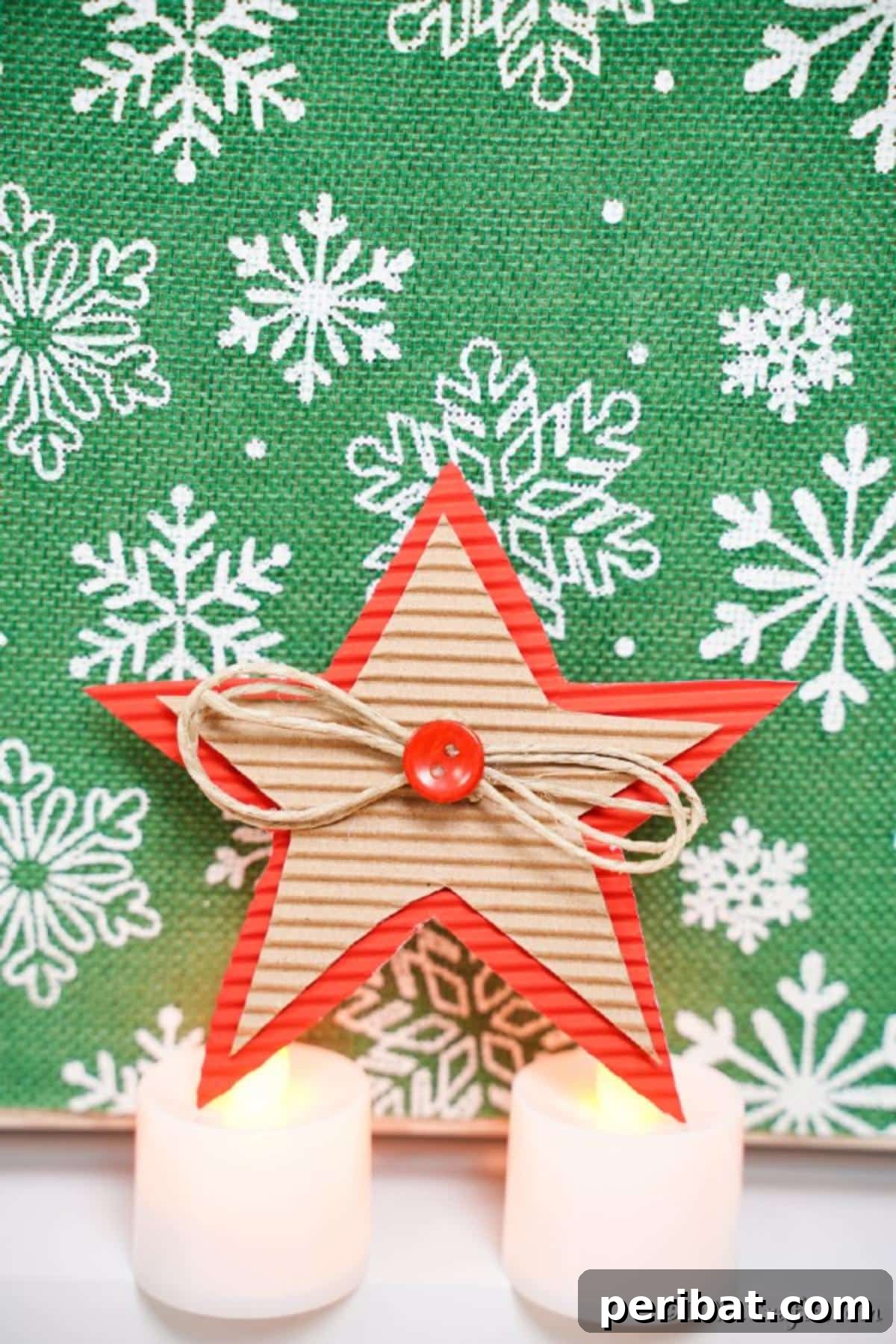 A cardboard Christmas star in front of green background with white snowflakes