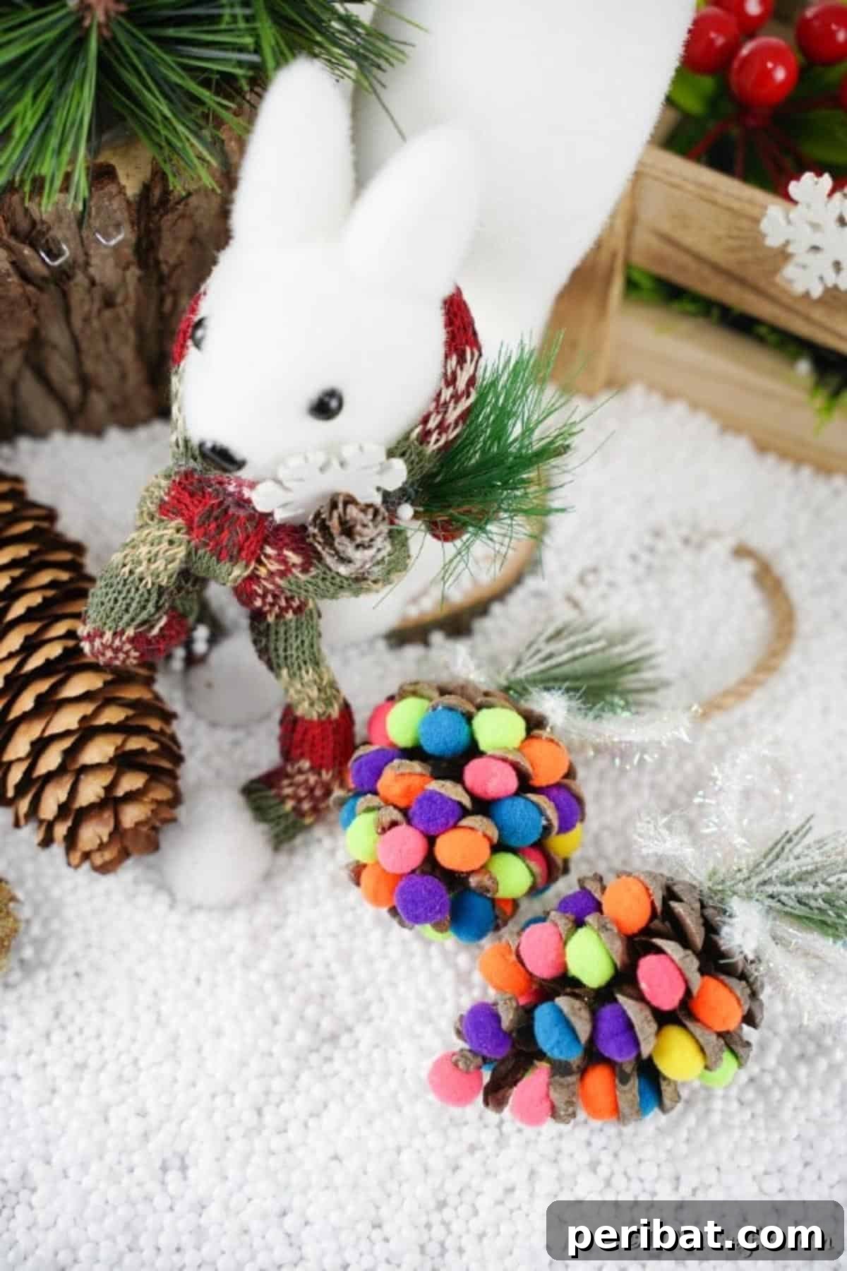 Vibrant Pinecone Christmas Decorations 10 Several finished colorful pinecone ornaments, artfully decorated with pom poms, resting on a surface covered with white 'snow' material.