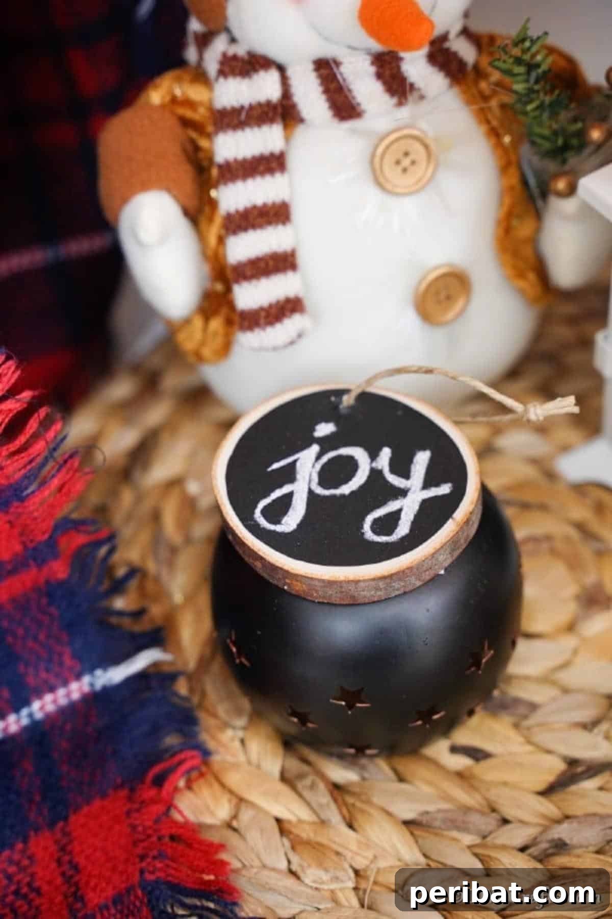 Rustic Wood Slice Chalkboard Charm 5 A rustic wood slice chalkboard ornament elegantly displayed on a tealight candle warmer, featuring a small, personalized message written in chalk, symbolizing cozy holiday decor.