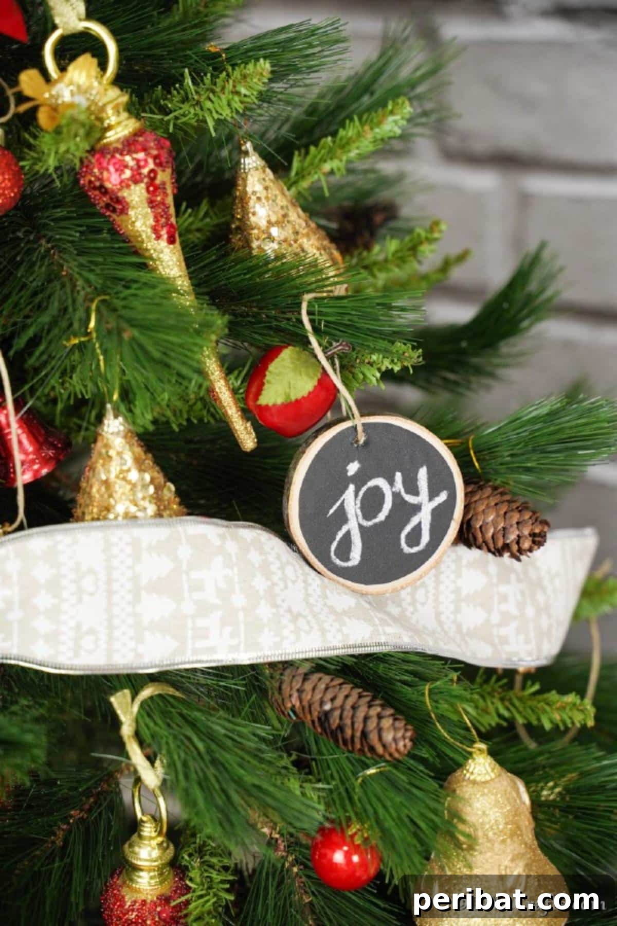 Rustic Wood Slice Chalkboard Charm 6 A beautifully personalized wood slice chalkboard ornament with 'Joy' written on it, hanging elegantly from a branch of a festive Christmas tree, showcasing handmade rustic holiday decor.