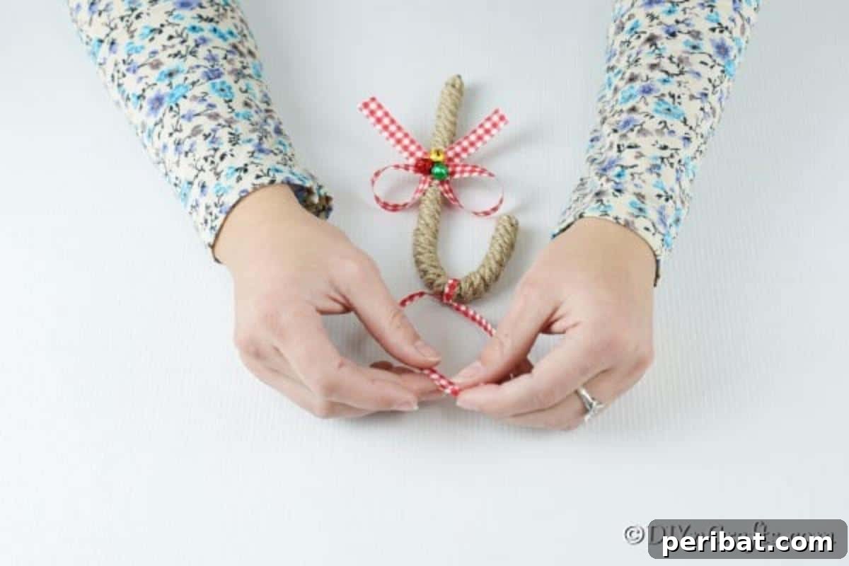 Farmhouse Jute Candy Cane Bauble 13 Tying a ribbon on the top of an ornament