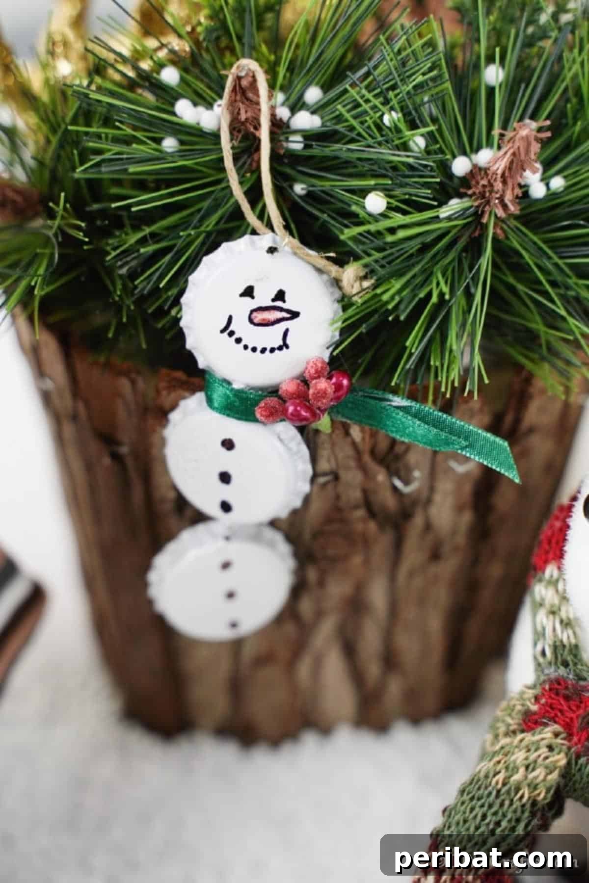 Upcycled Bottle Cap Snowman Charms 4 Bottle cap snowman ornament hanging on a wooden stump with greenery