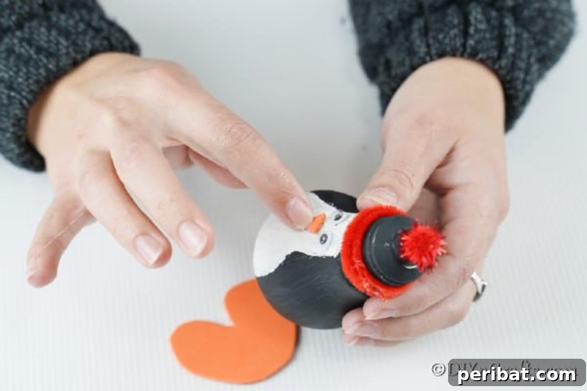 Gluing the orange foam paper feet to the penguin lightbulb