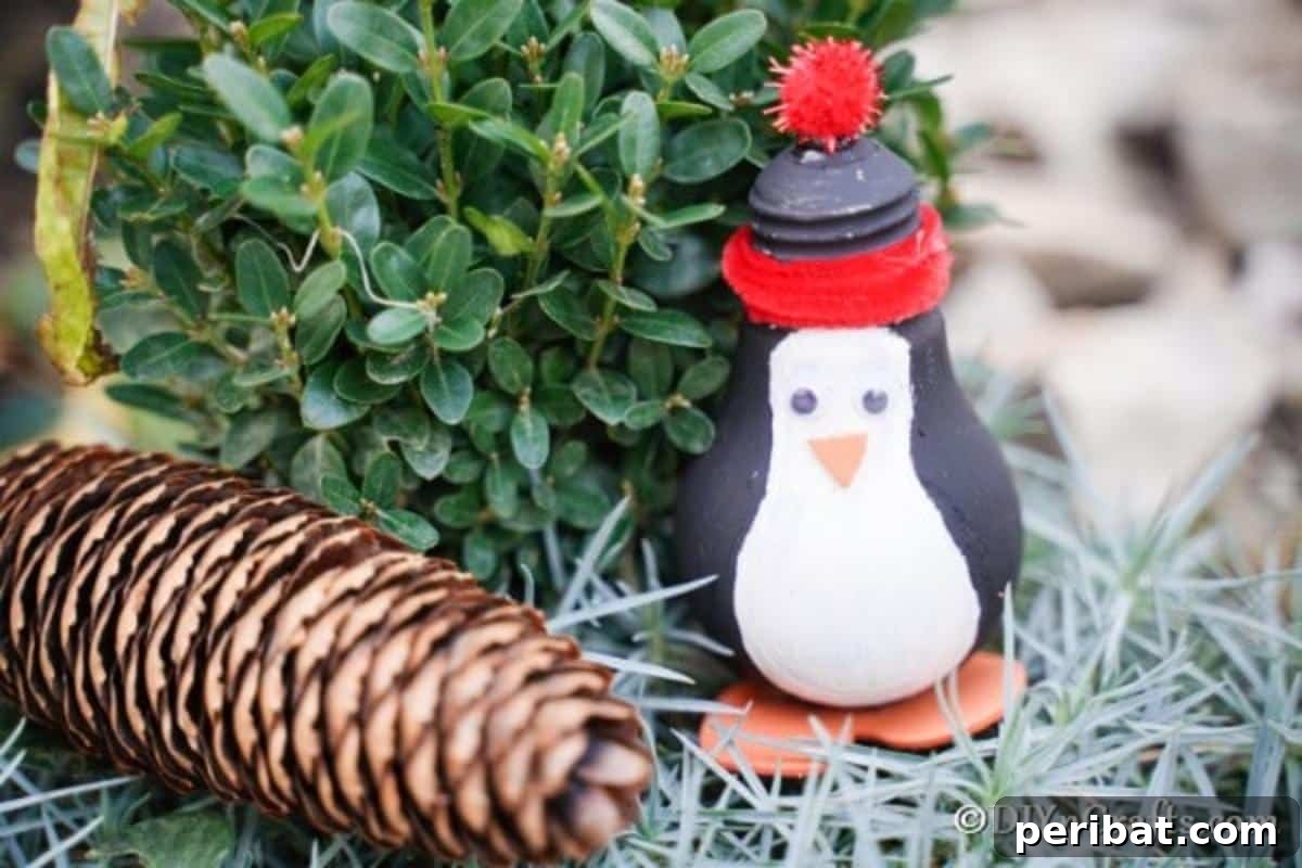 A penguin decoration on a bed of hay with pinecone next to it