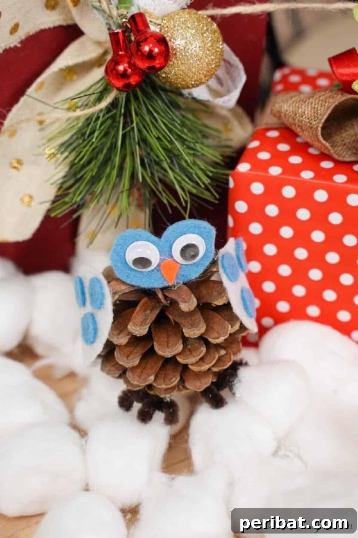 Whimsical Winter Pinecone Owl Decorations 14 A finished pine cone owl decoration sitting on cotton balls in front of wrapped presents