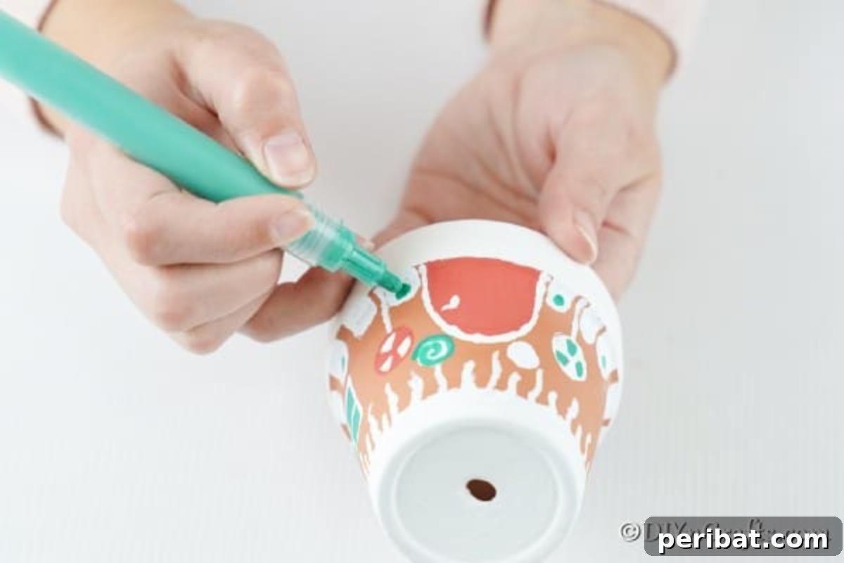 Adding colorful lollipops and delicate snowflakes to the gingerbread house clay pot for a festive look.