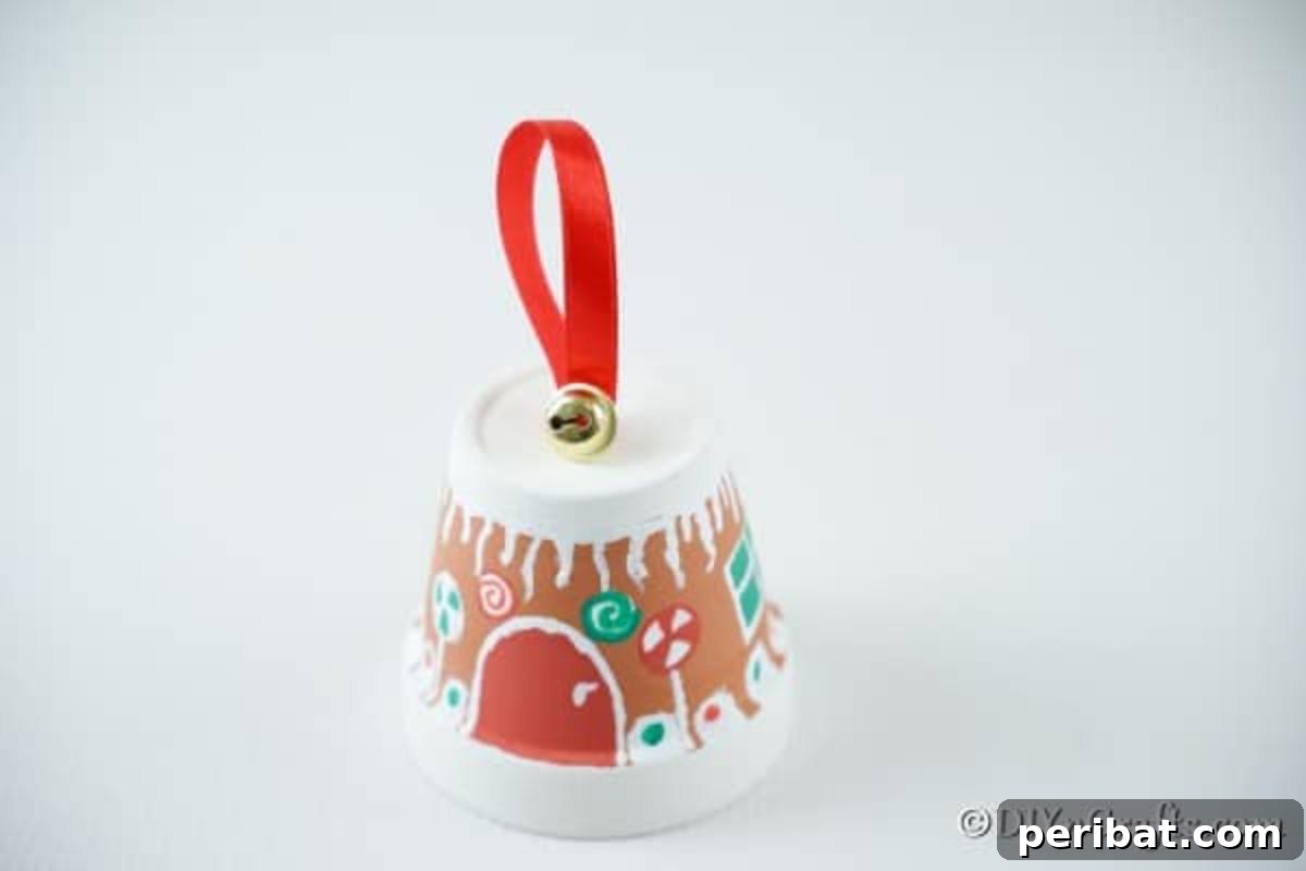 Attaching a decorative jingle bell with craft glue to the ribbon at the top of the gingerbread flower pot craft.