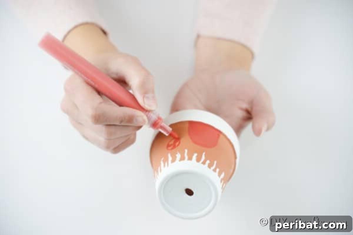 Drawing a cheerful red door onto the painted flower pot, serving as the entrance to the gingerbread house.