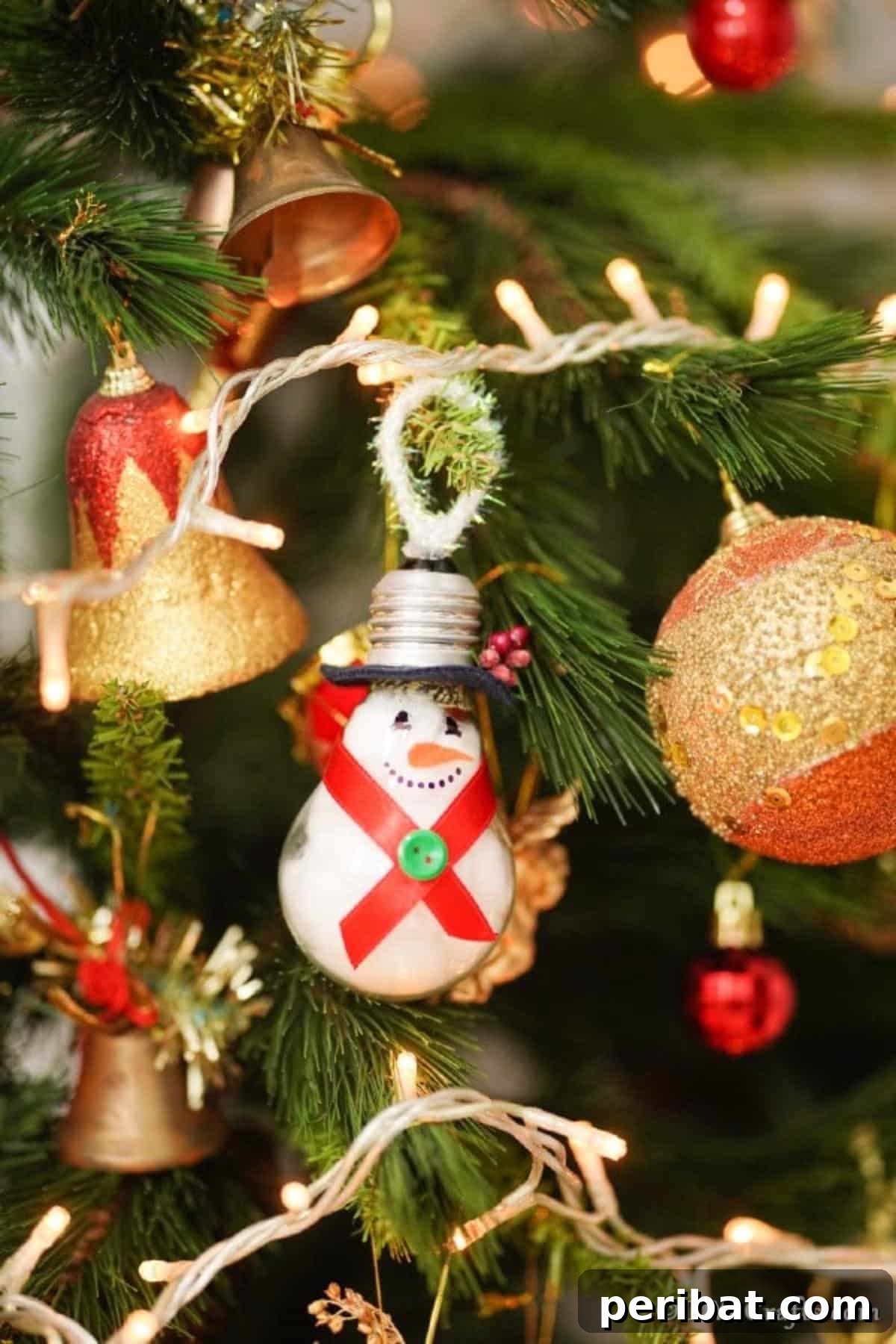 A beautifully completed light bulb snowman ornament proudly hanging on a festive Christmas tree, ready for the holidays