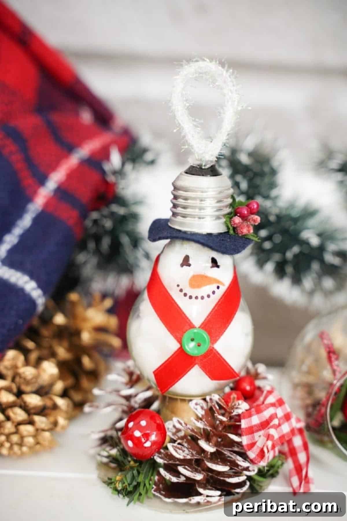 A light bulb snowman ornament resting on a table, surrounded by various festive holiday decorations