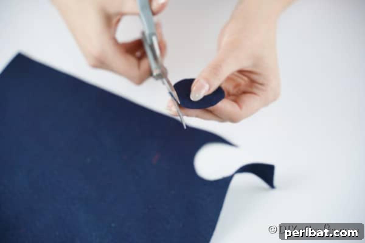 Image showing a circular piece of black felt being cut to form the base of the snowman's hat, ready for assembly