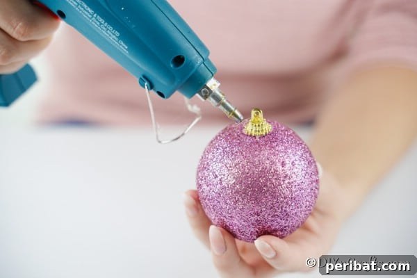 Adding glue to the top of a Christmas ball to create icing