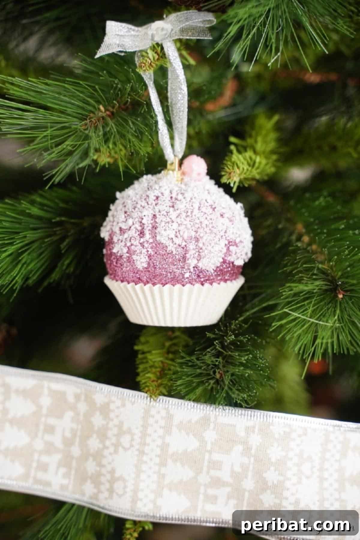 Sparkling DIY Cupcake Christmas Ornaments 4 A charming cupcake ornament hanging delicately on a Christmas tree branch, surrounded by other festive decorations