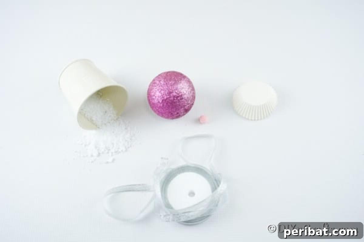 Sparkling DIY Cupcake Christmas Ornaments 6 A neatly arranged collection of supplies needed to craft a festive muffin ornament, including a glitter ball, muffin cup, fake snow, and hot glue gun