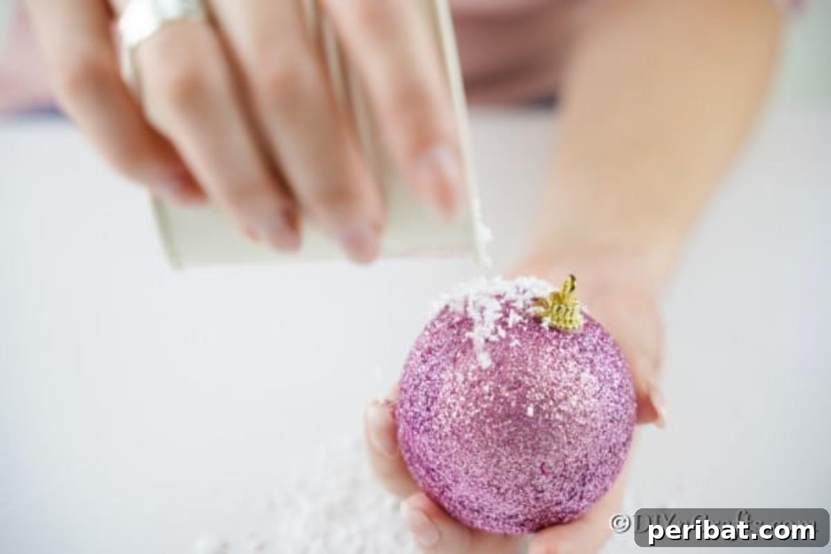 Sparkling DIY Cupcake Christmas Ornaments 8 Sprinkling fake snow over the recently applied hot glue on a Christmas ball to create a sparkly 'icing' effect