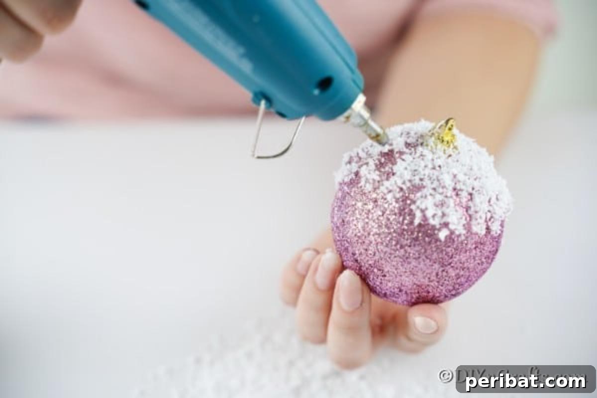 Sparkling DIY Cupcake Christmas Ornaments 9 Continuing to apply 'icing' with hot glue and fake snow to fully coat the top of the Christmas ball, forming a muffin ornament