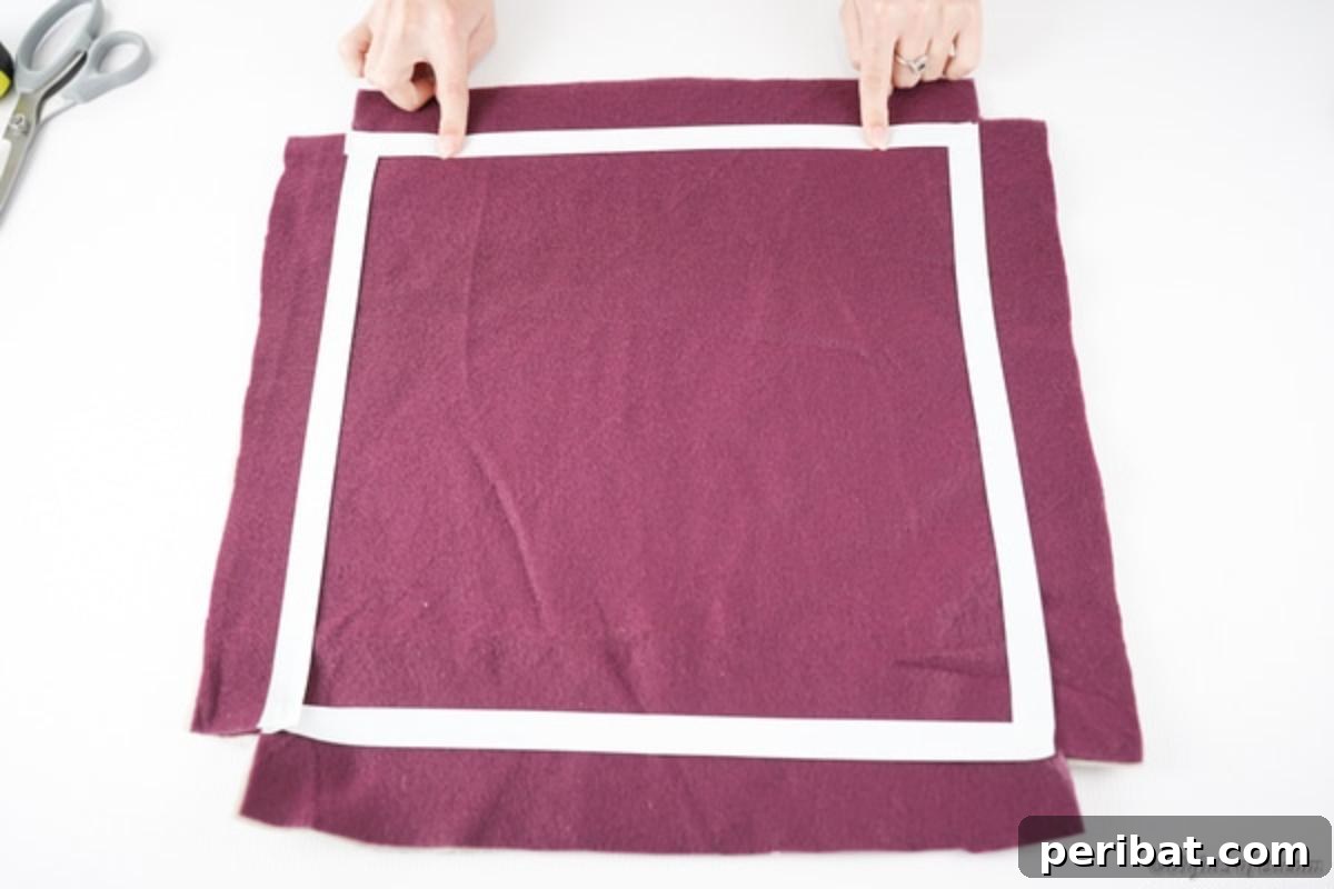 Easy 30-Minute No-Sew Reversible Fleece Pillow 8 Applying painter's tape to the stacked fabric to create a precise guideline for cutting the fringe.