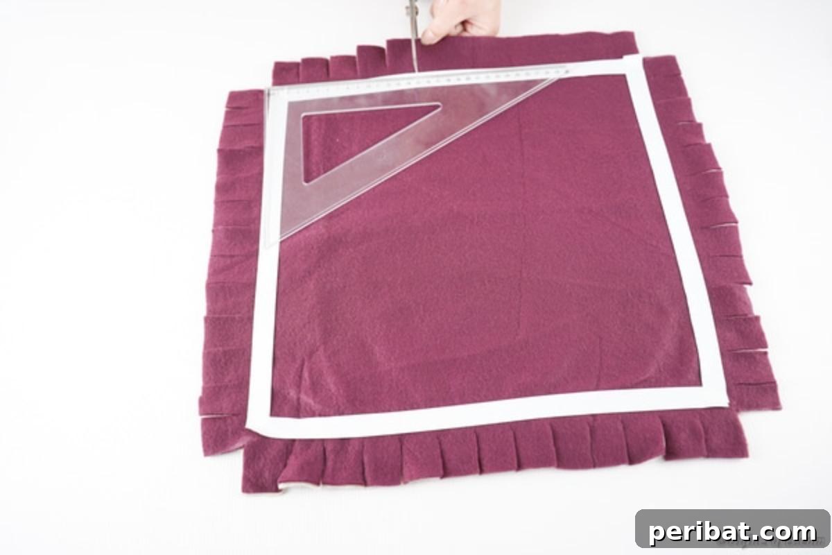 Easy 30-Minute No-Sew Reversible Fleece Pillow 10 The complete square of fabric, now with evenly cut fringe strips along all edges.