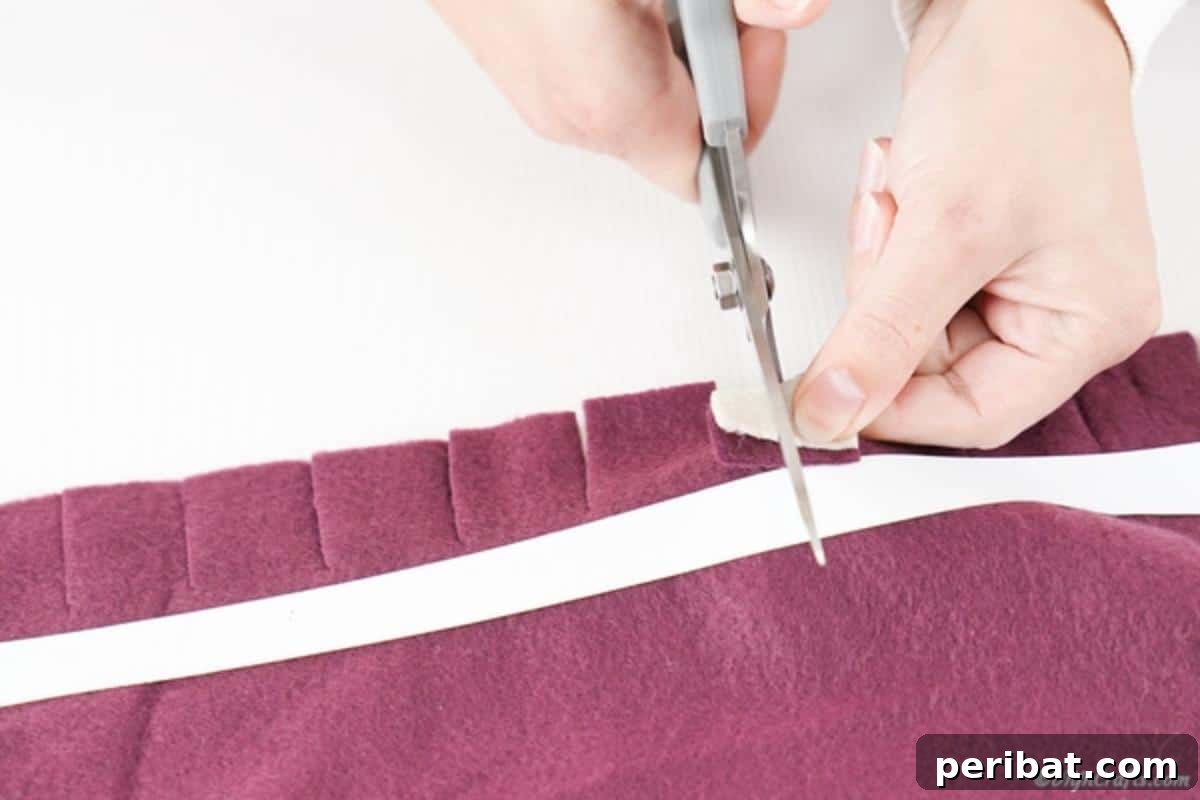 Easy 30-Minute No-Sew Reversible Fleece Pillow 11 Demonstration of cutting a small slit into a folded fringe piece, creating a keyhole for weaving.