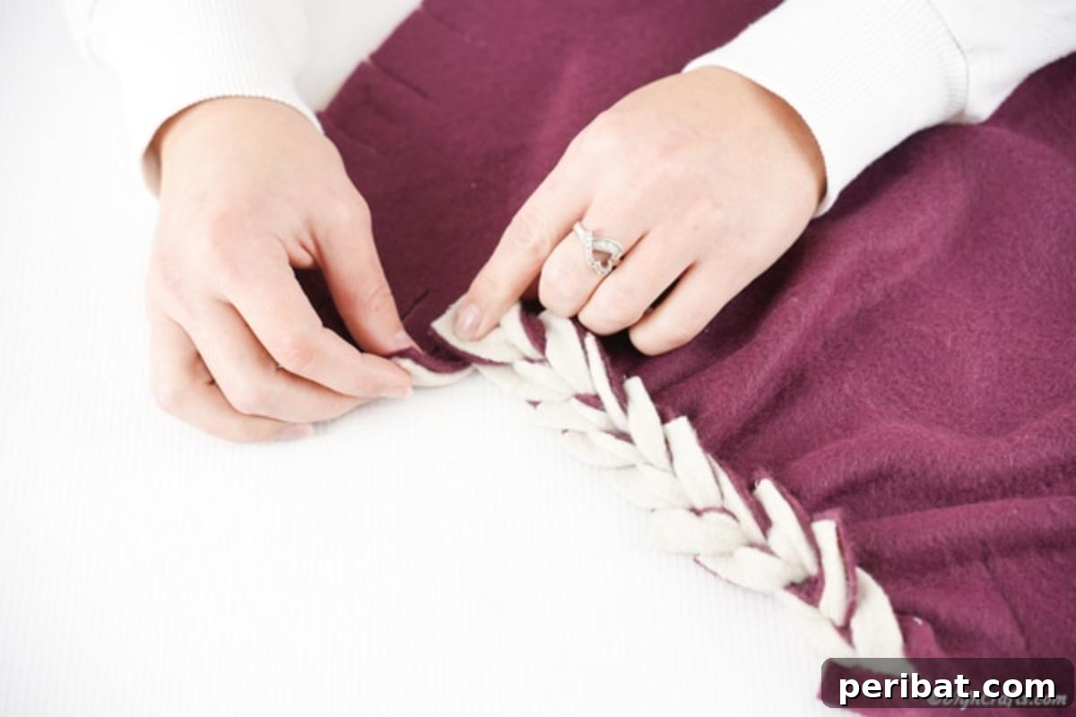 Easy 30-Minute No-Sew Reversible Fleece Pillow 13 The initial stages of weaving fabric fringes together to form a braided pattern on the pillowcase edge.