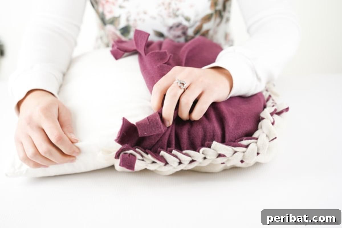 Easy 30-Minute No-Sew Reversible Fleece Pillow 15 Carefully stuffing the partially woven no-sew pillowcase with an existing throw pillow.