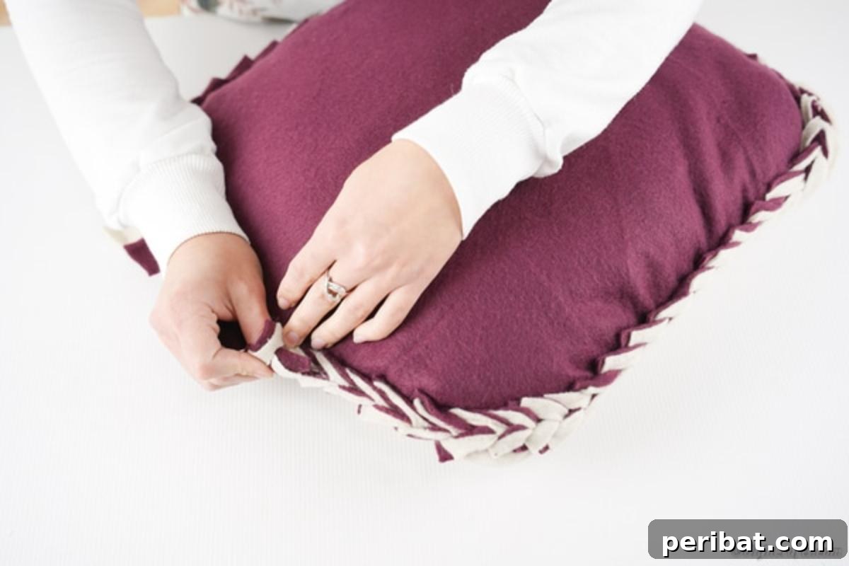 Easy 30-Minute No-Sew Reversible Fleece Pillow 16 Completing the weaving on the final side of the no-sew throw pillow, securing the filling inside.