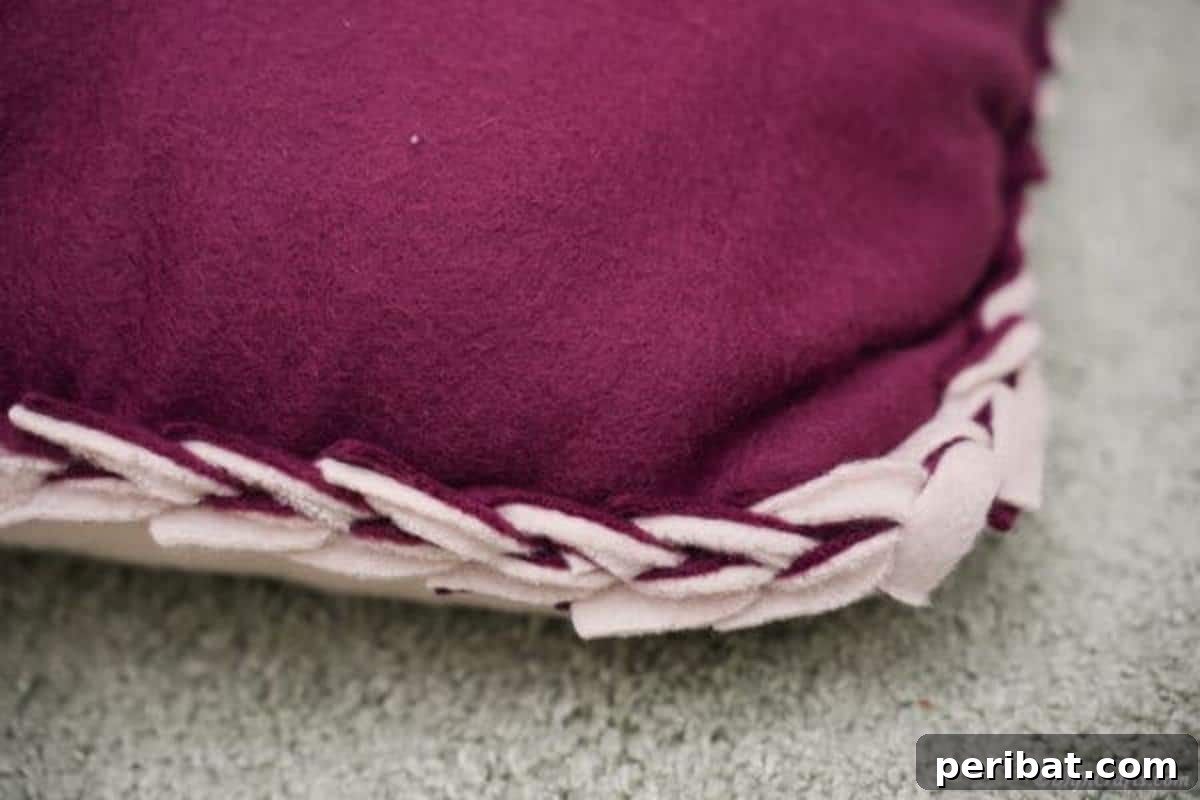 Easy 30-Minute No-Sew Reversible Fleece Pillow 17 A close-up view of the intricately woven fabric edge, showcasing the braided detail of the no-sew pillow.