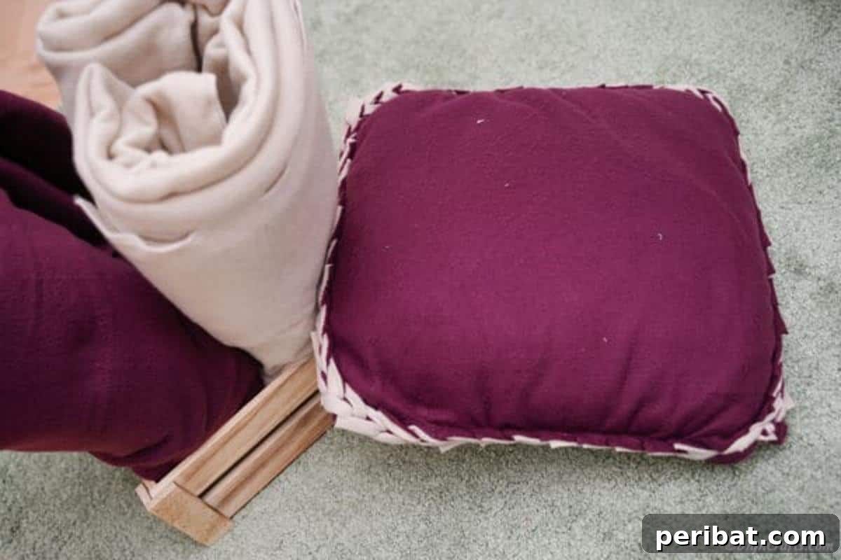 Easy 30-Minute No-Sew Reversible Fleece Pillow 3 A charming purple and lavender no-sew reversible pillow resting on a wooden floor.