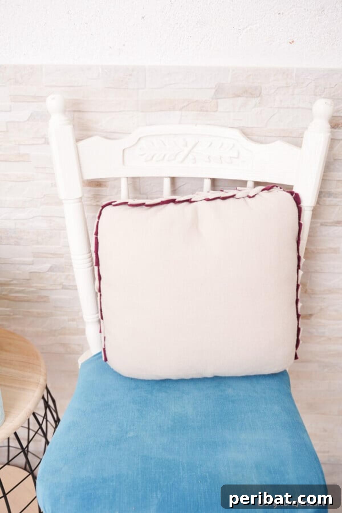 Easy 30-Minute No-Sew Reversible Fleece Pillow 19 A charming light purple no-sew pillow resting on a white chair with a blue cushion, ready for display.