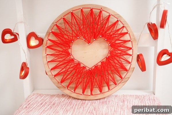 Heart string art in front of white wall with paper heart garland
