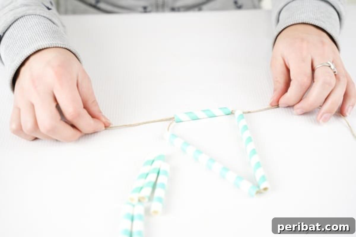 Twine being tied around three paper straws, securely fastening them together to form a stable triangular segment of the planter.