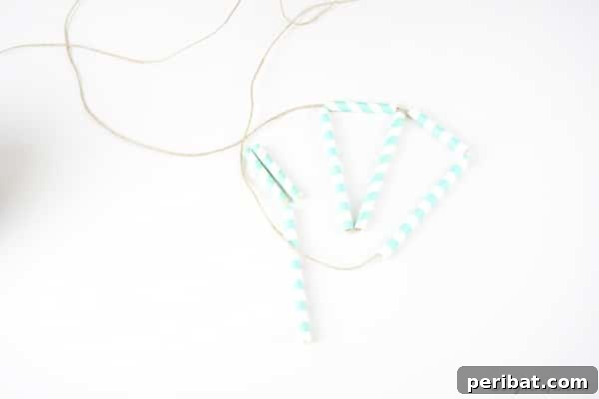 Hands meticulously adding a second set of paper straws to the developing planter pattern, extending the geometric design.