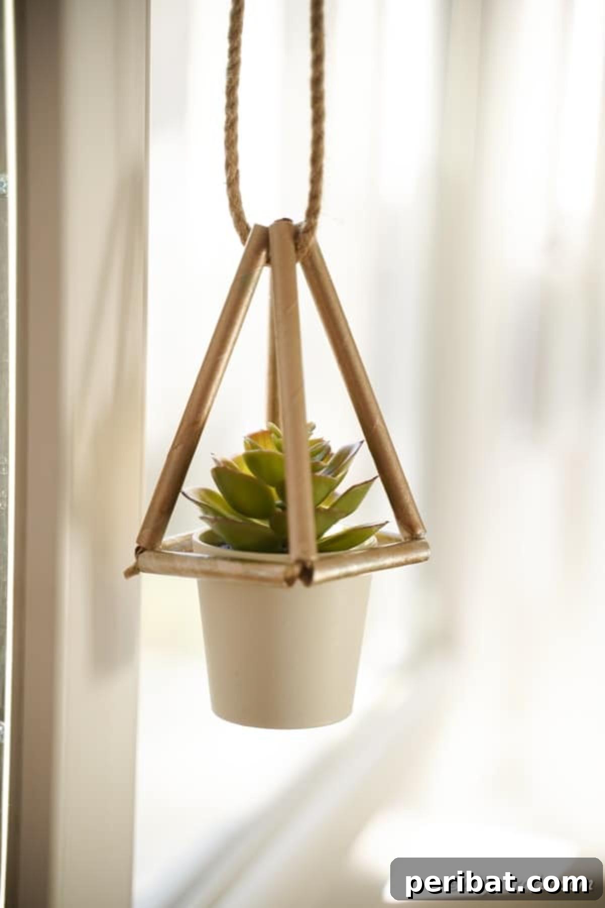 A charming homemade succulent planter, crafted from delicate paper straws, gracefully hangs near a sunlit window, bringing natural beauty indoors.