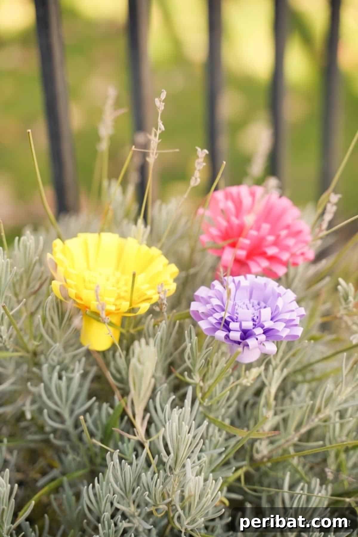 Vibrant yellow, pink, and purple paper flowers beautifully arranged on a green shrub outdoors
