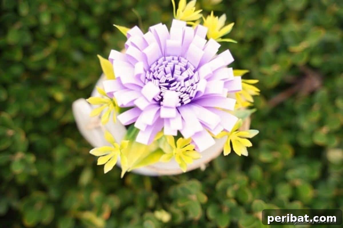 A vibrant paper flower, rich in color, sits gently on a lush green shrub