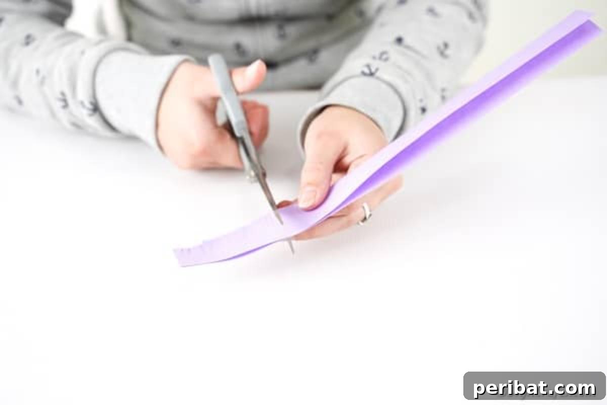 Hands carefully cutting fringes into a folded strip of colored paper