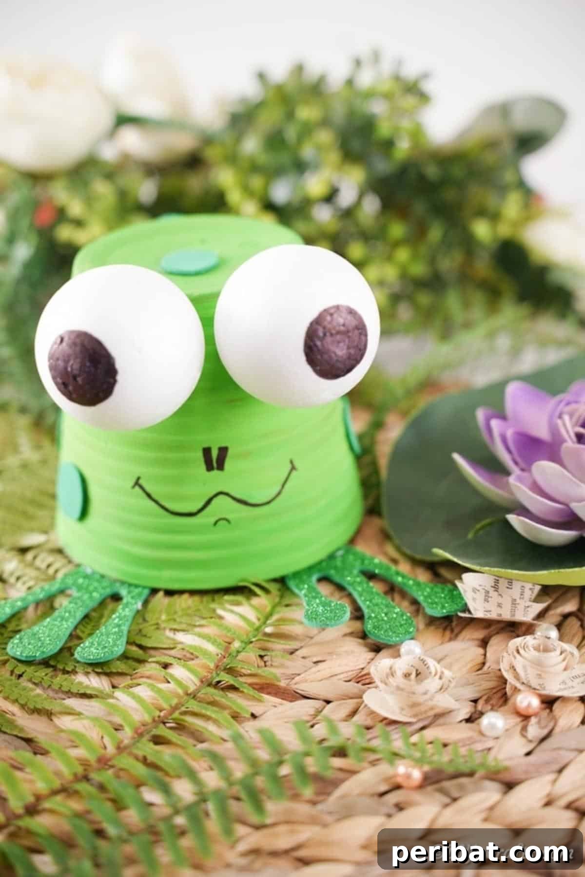 Whimsical Upcycled Flowerpot Frog Garden Art 5 A meticulously crafted flower pot frog, featuring vibrant green paint and expressive eyes, carefully placed amidst delicate fern fronds, showcasing its artistic appeal as bespoke garden art.