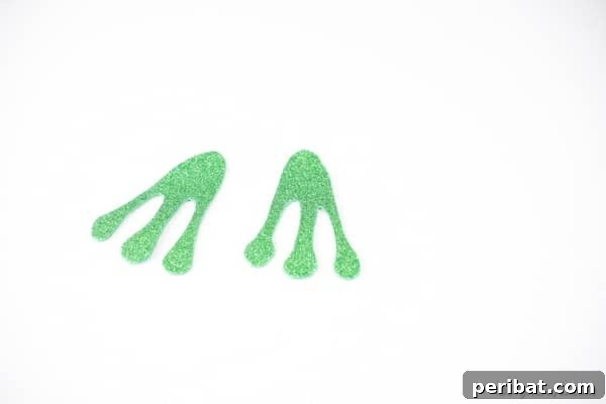 Whimsical Upcycled Flowerpot Frog Garden Art 10 Close-up of two distinct frog feet, cut from glitter green foam paper, ready to be attached to the flower pot frog craft.