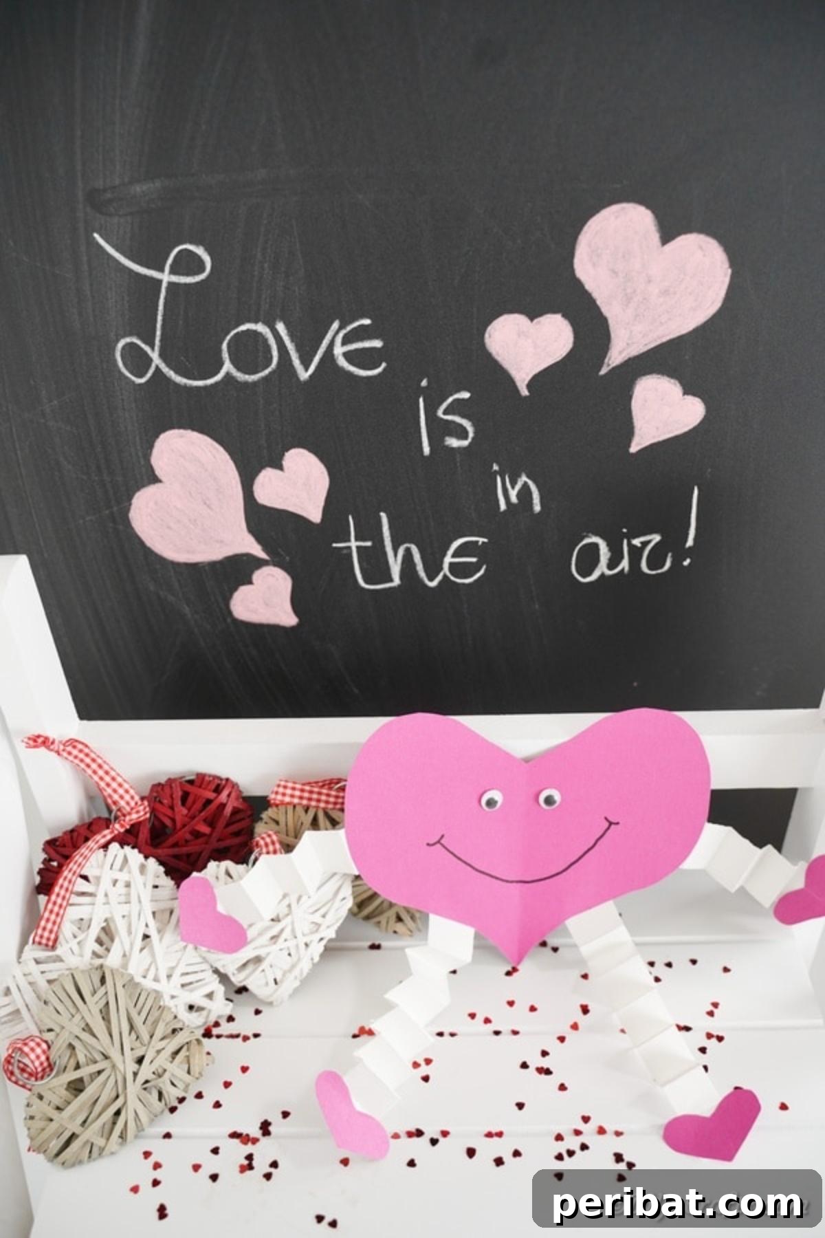 Little Hands, Loving Hearts: Kids' Valentine Paper Craft 5 Smiling pink paper heart on a shelf in front of a chalkboard