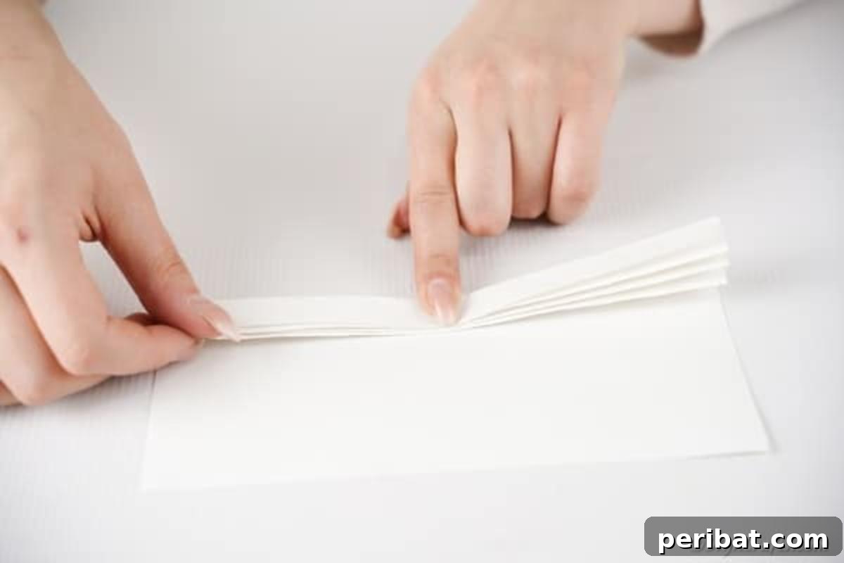 Little Hands, Loving Hearts: Kids' Valentine Paper Craft 10 Demonstration of folding white paper into an accordion or fan shape