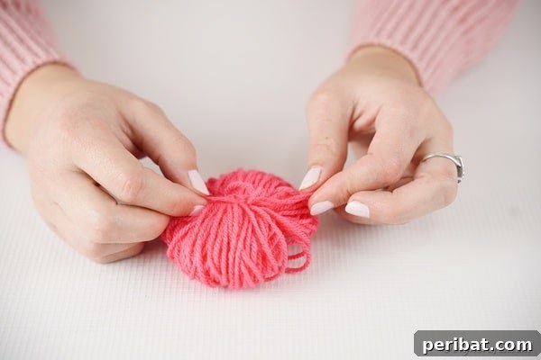 Tying yarn in center of pom pom