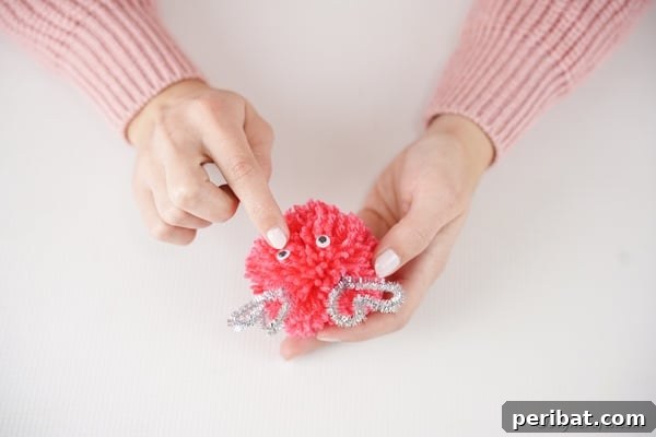 Gluing Googly eyes in place on pom pom monster