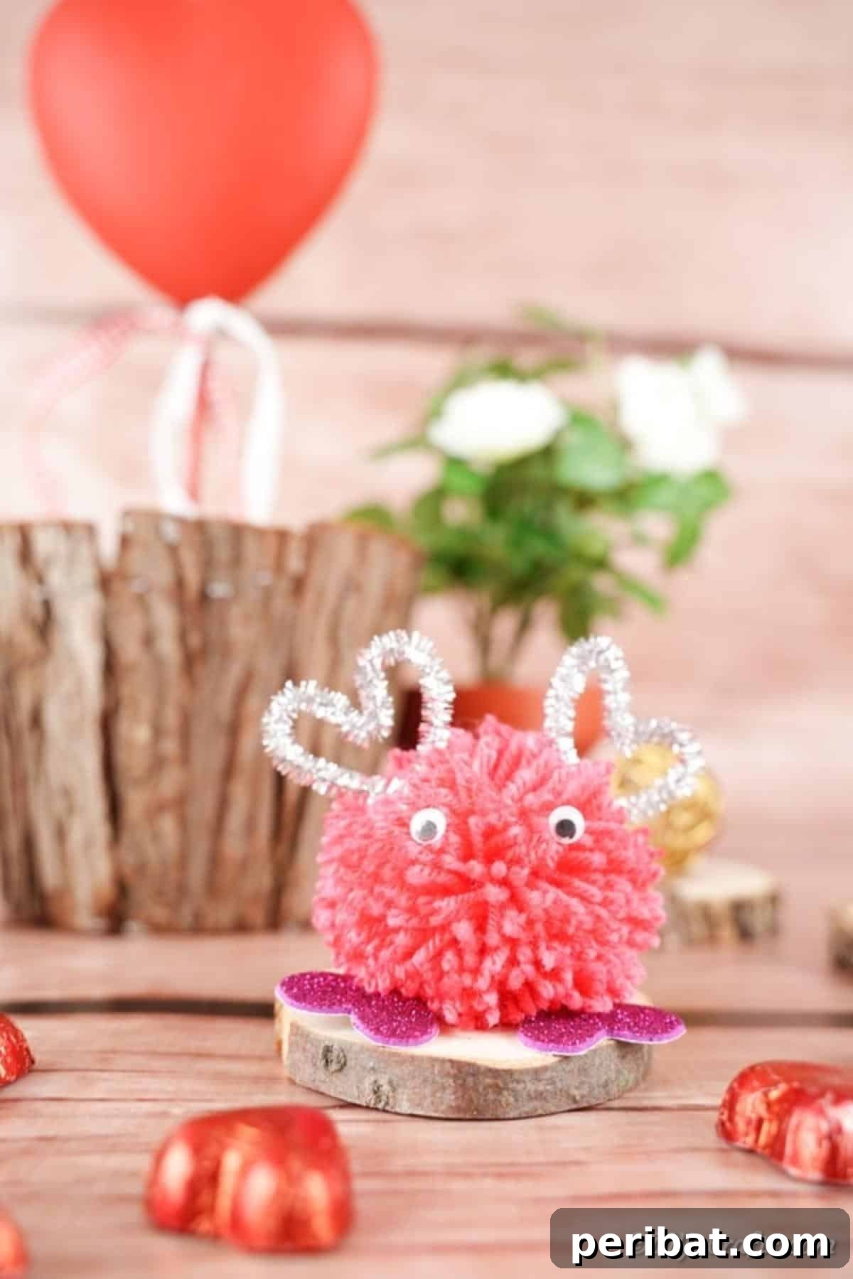 Valentine's day pom pom monster in front of wooden stump