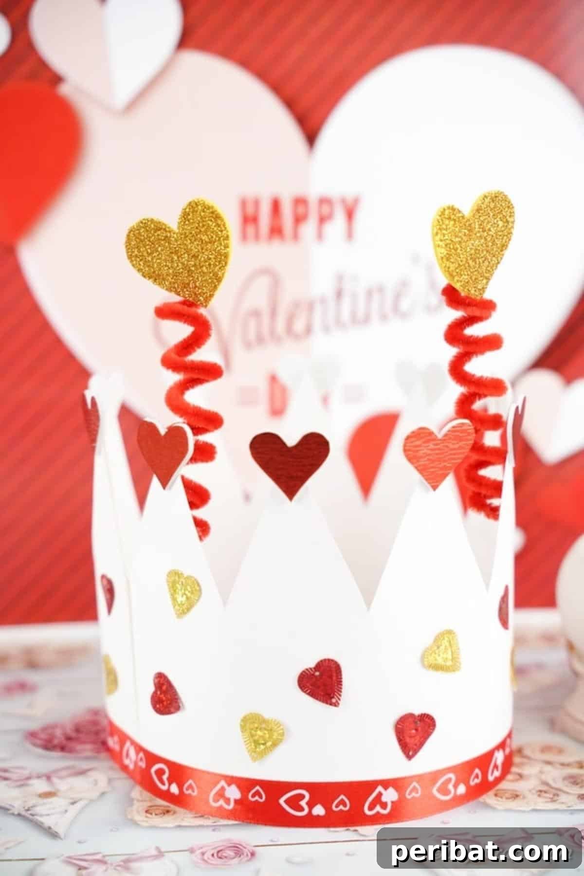 Easy Valentine Paper Crown Craft for Children 4 A finished Valentine's paper crown, adorned with hearts and glitter, sits in front of a festive Valentine's Day sign.