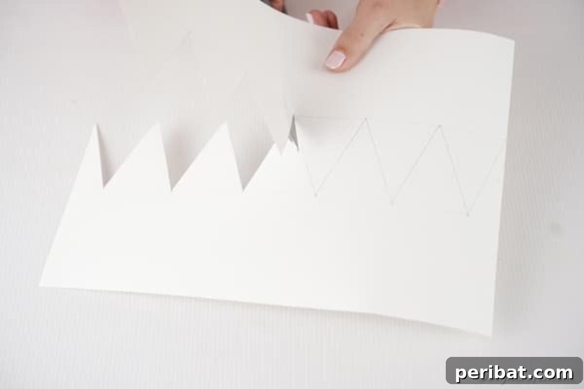 Easy Valentine Paper Crown Craft for Children 8 Hands carefully cut along the drawn outline of a crown from a sheet of paper, demonstrating the precision needed for the craft.