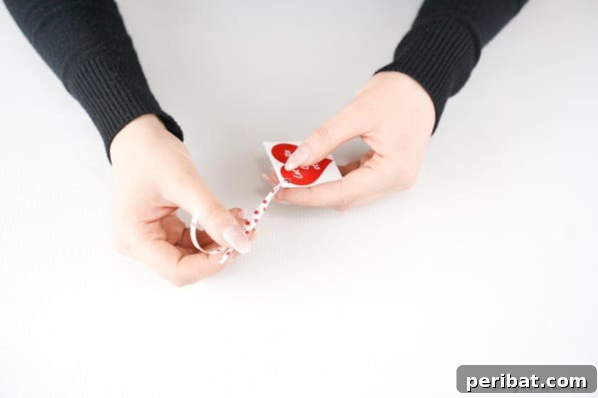 Make Your Own Valentine's Love Arrows 13 Tying a small heart-shaped gift tag with ribbon onto a Valentine's Day pencil, adding a personal touch