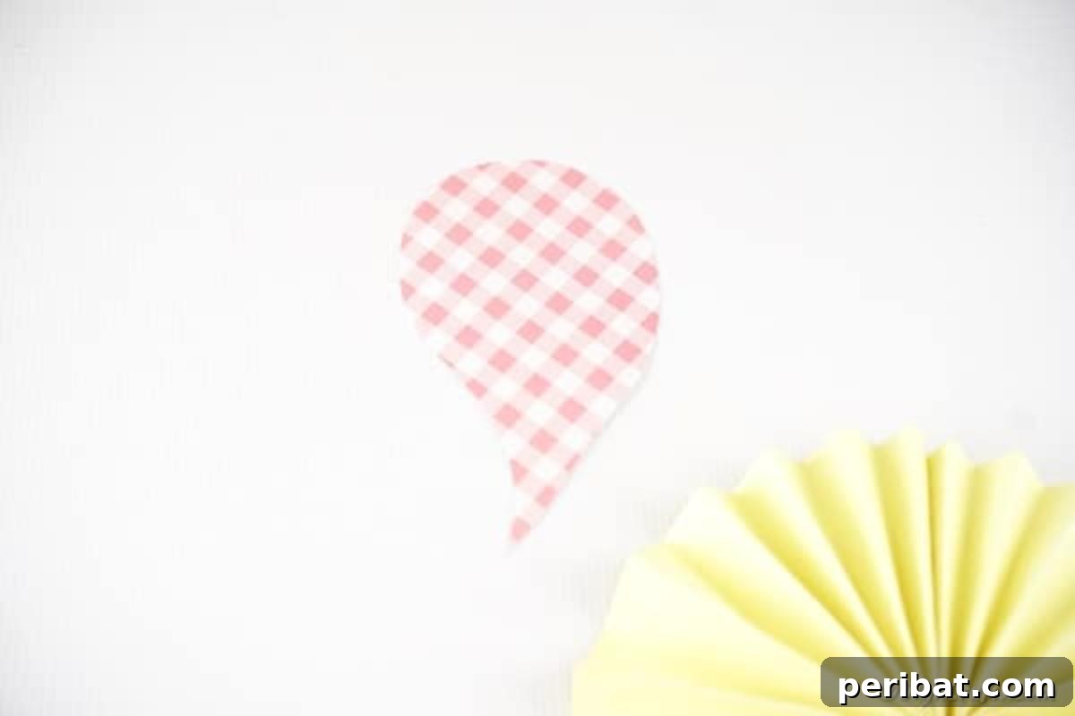 Simple & Sweet: Crafting Paper Birds with Kids 11 A hand holding scissors, carefully cutting out a simple wing shape from a piece of patterned paper, which will be attached to the bird's body.