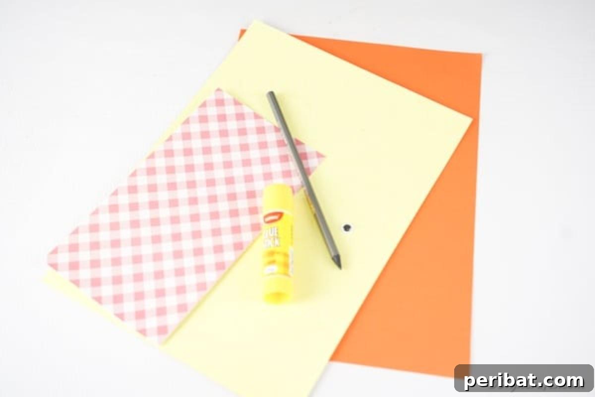 Simple & Sweet: Crafting Paper Birds with Kids 6 An organized array of craft supplies laid out on a clean surface, including yellow, orange, and patterned paper sheets, a glue stick, scissors, a pen, and googly eyes, all ready for the paper bird craft project.
