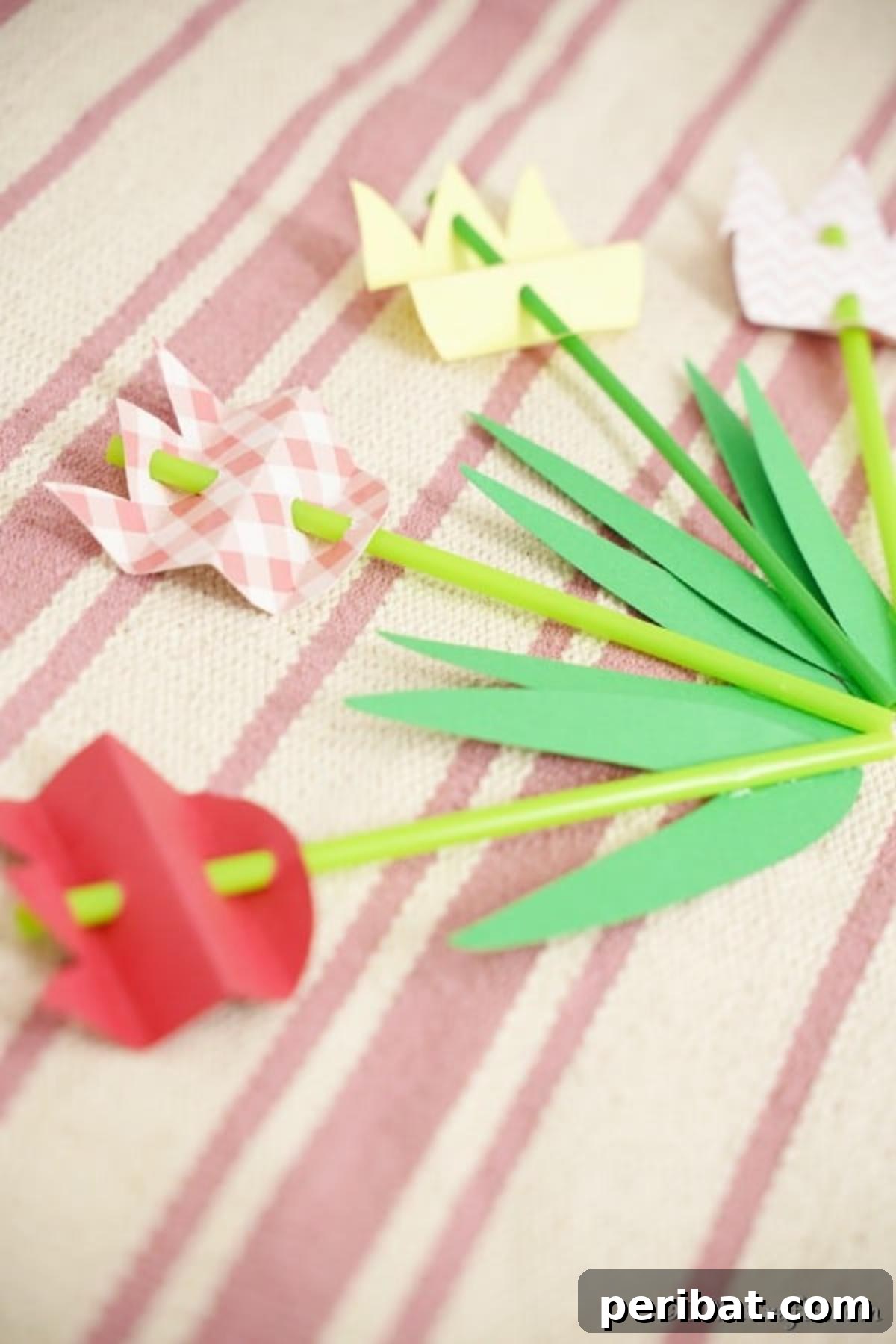 Create Charming Spring Paper Tulips 6 Collection of colorful paper tulips resting on a vibrant striped pink surface