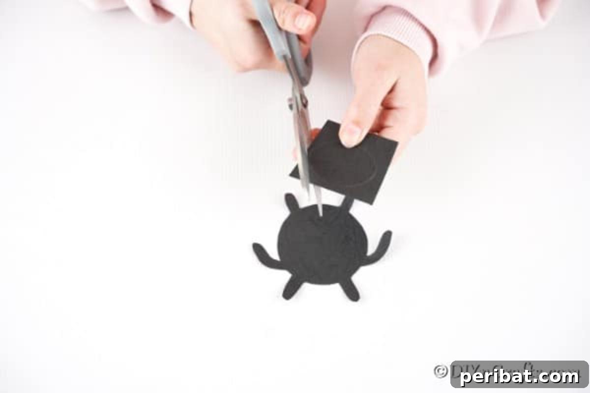 Adorable Upcycled Ladybug Planter Craft 11 Black craft paper being cut into the shapes for the ladybug's legs and oval face.